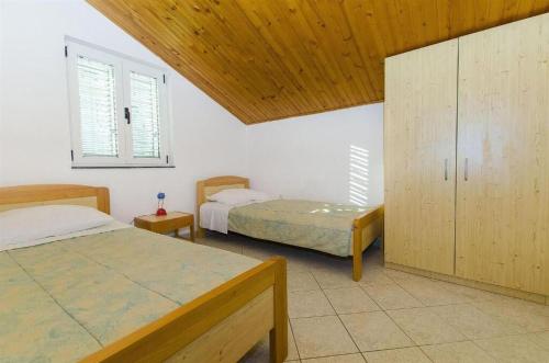 1 dormitorio con 2 camas y techo de madera en Apartments Nada, en Grebaštica