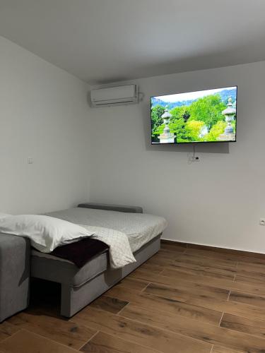 a bedroom with a bed and a flat screen tv on the wall at Guest House Ivan in Donji Zemunik