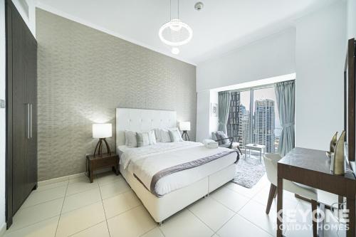 a white bedroom with a bed and a balcony at Lavish One Bedroom with Amazing Sun Deck & Pool in Dubai
