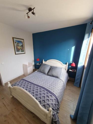 a bedroom with a bed with a blue wall at La framboisette in Le Vaudreuil