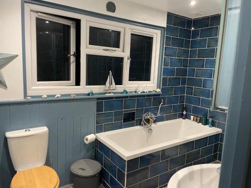 a blue tiled bathroom with a sink and a toilet at Cissbury in Midhurst