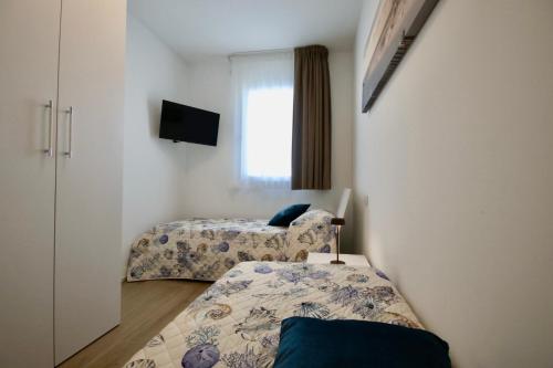 Duas camas num pequeno quarto com uma janela em Blu Homes Apartments EfStyle Hotel em Lido di Jesolo