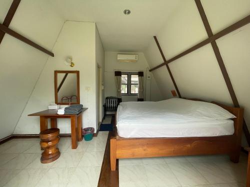 1 dormitorio con cama, mesa y espejo en Popeye House en Mae Hong Son
