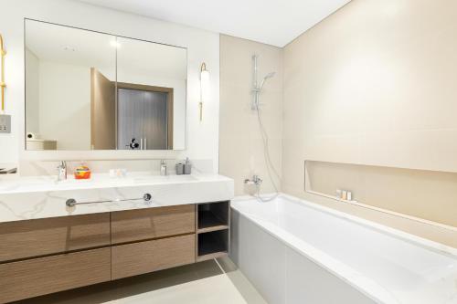 een badkamer met een wastafel, een bad en een spiegel bij Vacay Lettings - Getaway home Dubai Creek Harbour in Dubai