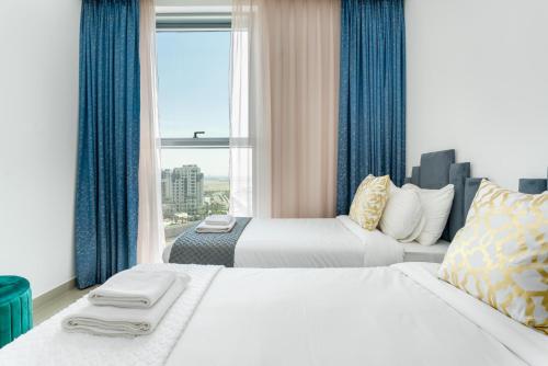 two beds in a hotel room with a window at Vacay Lettings - Getaway home Dubai Creek Harbour in Dubai