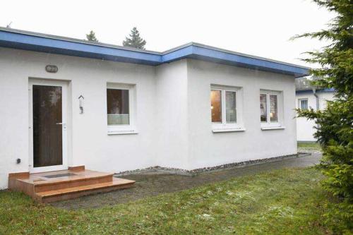 ein weißes Haus mit einer Veranda und einer Tür in der Unterkunft Ferienhaus "Strandperle" in Lubmin