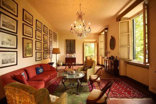 a living room with a red couch and a table at Villa Trenta Prestigious Villa Enchanting Garden in Lucca