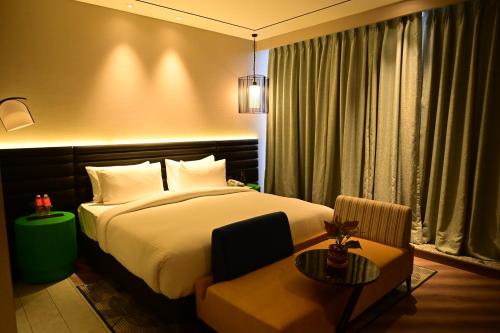 a bedroom with a bed and a chair and a table at Ramada Encore by Wyndham Bareilly Civil Lines in Bareilly