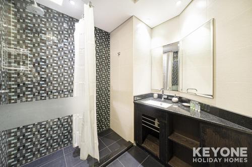 a bathroom with a sink and a shower with a mirror at Lavish One Bedroom with Amazing Sun Deck & Pool in Dubai