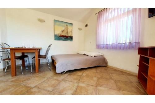 Schlafzimmer mit einem Bett, einem Tisch, einem Tisch und einem Fenster in der Unterkunft Apartments Villa Višnja in Pašman