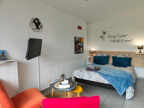 een slaapkamer met een bed en een tafel en stoelen bij LE GARDEN CENTRAL STUDIO in Dinan