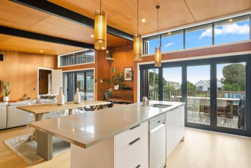a kitchen with white cabinets and a large window at Beachside Sanctuary - Otaki Beach Holiday Home in Otaki Beach