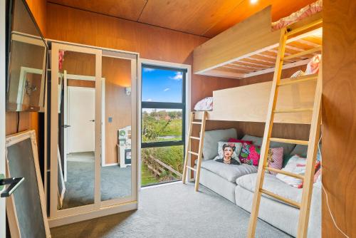 a room with bunk beds and a sliding glass door at Beachside Sanctuary - Otaki Beach Holiday Home in Otaki Beach
