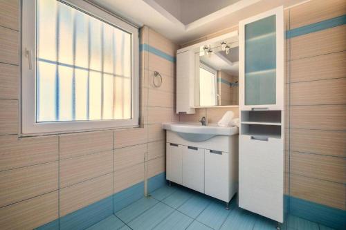 ein Bad mit einem Waschbecken und einem Fenster in der Unterkunft Villa Nikolitsa with private beach in Megara