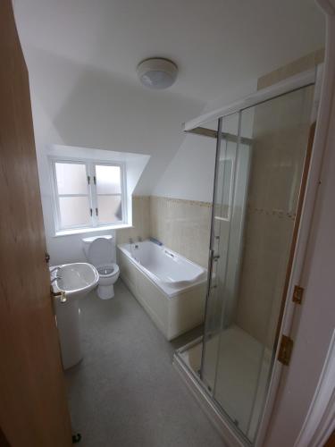 a bathroom with a tub and a toilet and a sink at Crew's Apartment in Dungarvan