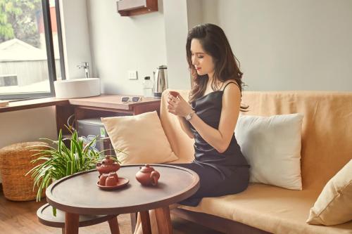 a woman sitting on a couch with a table at Entire Cosy Apartments May Homestay Hanoi in Hanoi