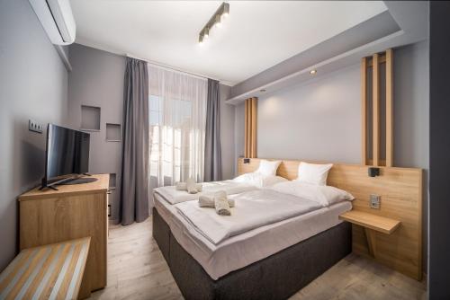 1 dormitorio con 1 cama grande y TV en Park Hotel Ambrózia, en Hajdúszoboszló