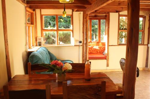 a living room with a table and a couch and windows at ChacraKremen in El Bolsón