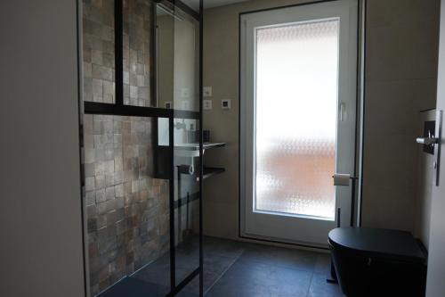 a bathroom with a glass shower door and a window at Rosenheim in Saas-Grund
