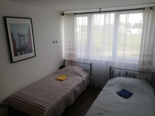 two beds in a room with a window at Bridge Apartments Klaipeda in Klaipėda