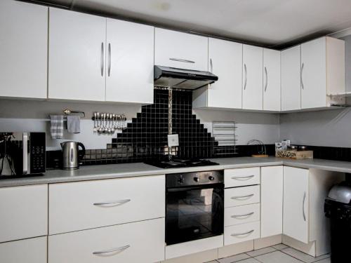 a kitchen with white cabinets and a stove top oven at Zulia home in Pretoria