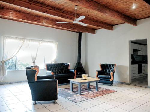 een woonkamer met stoelen en een tafel en een plafond bij Zulia home in Pretoria
