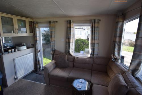 a living room with a couch and a window at Tim's Getaways Super Caravan A2, Todber Valley Caravan Park in Gisburn
