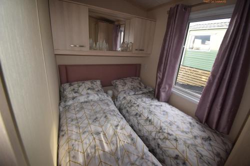 two beds in a small room with a window at Tim's Getaways Super Caravan A2, Todber Valley Caravan Park in Gisburn