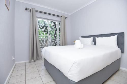 a white bed in a room with a window at Comfy Hatfield Appartment in Pretoria