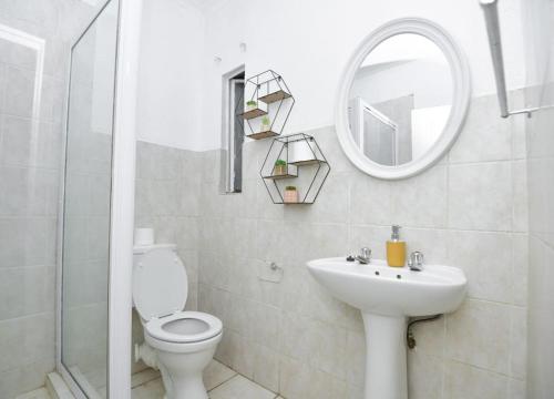 La salle de bains est pourvue de toilettes, d'un lavabo et d'un miroir. dans l'établissement Comfy Hatfield Appartment, à Pretoria