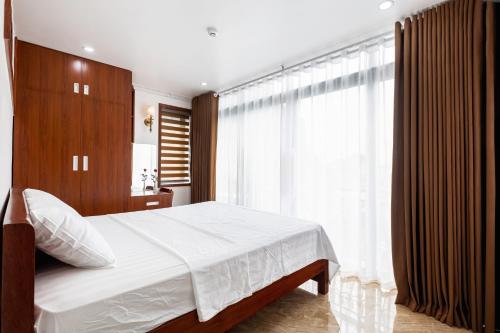 a bedroom with a white bed and a large window at CHÉRIE HOMEHOTEL in Ha Long
