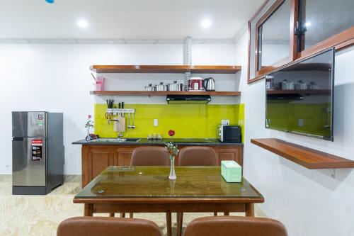 a kitchen with a table and a yellow wall at CHÉRIE HOMEHOTEL in Ha Long