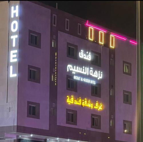 a building with neon signs on the side of it at فندق نزهة النسيم in Ash Shishah