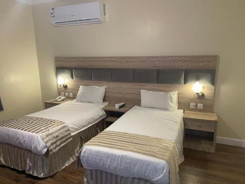 a hotel room with two beds and a desk at Nuzhat Al Naseem Hotel in Mecca