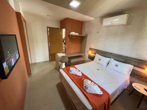 ein Hotelzimmer mit einem Bett und einem Flachbild-TV in der Unterkunft Cidade Jardim Apart in Guaramiranga
