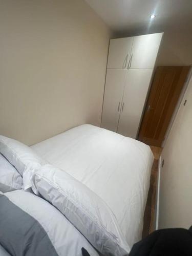 2 Bedroom Apartment,Chester Road N17 في لندن: غرفة نوم مع سرير أبيض وخزانة