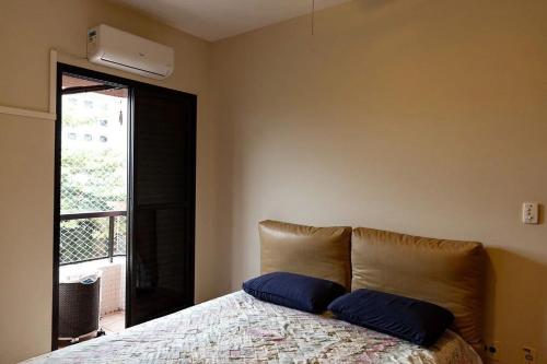 ein Schlafzimmer mit einem Bett mit zwei blauen Kissen darauf in der Unterkunft Condomínio Edifício Allamanda - Módulo 6 in Bertioga