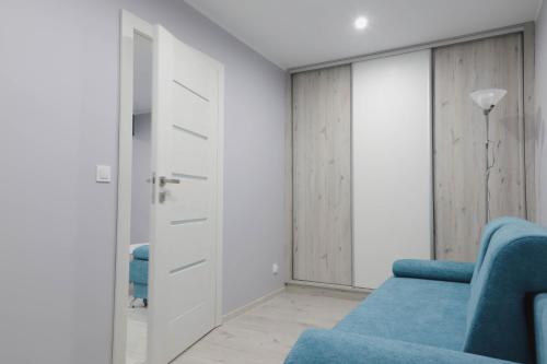 salon z niebieską kanapą i drzwiami w obiekcie Apartament z Balkonem w Jastrzębiu Zdroju