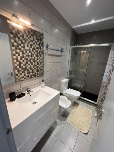La salle de bains blanche est pourvue d'un lavabo et de toilettes. dans l'établissement Mare Verde A10, à Adeje