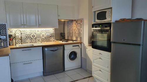 une cuisine avec des armoires blanches et une laveuse et une sécheuse dans l'établissement Horizon, à Saint-Valery-en-Caux