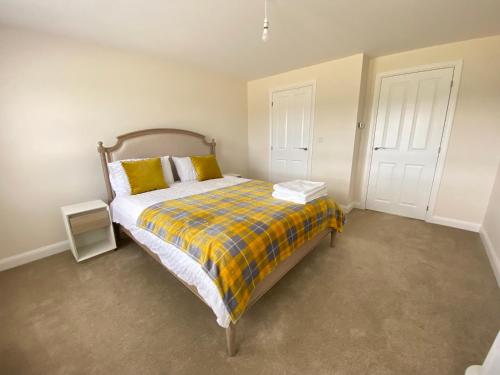 a bedroom with a bed with a plaid blanket at Westergate - 4 Bed Luxury Home with free parking in Milton Keynes