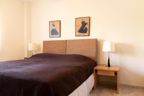 een slaapkamer met een bed en twee foto's aan de muur bij Casa Higuera in Mutxamel