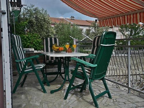 una mesa y sillas en un patio en Apartment Lucia en Omišalj