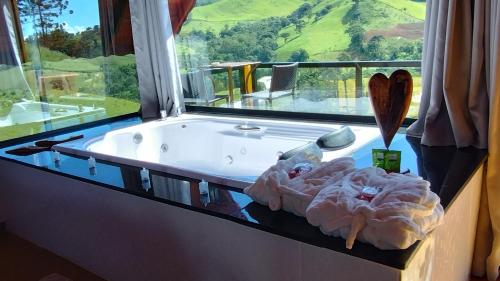 uma banheira num quarto com uma grande janela em Chales Sabor Dos Ventos em Gonçalves