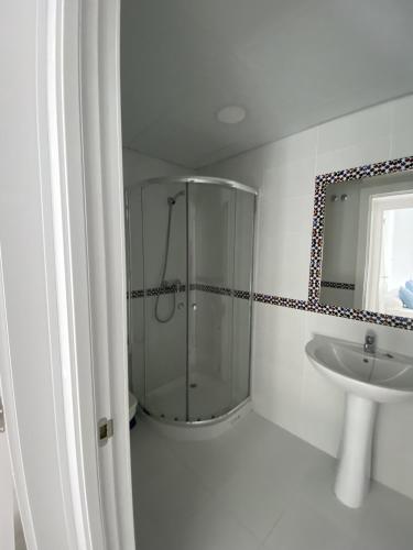 ein weißes Bad mit einer Dusche und einem Waschbecken in der Unterkunft Apartamento Carihuela in Torremolinos