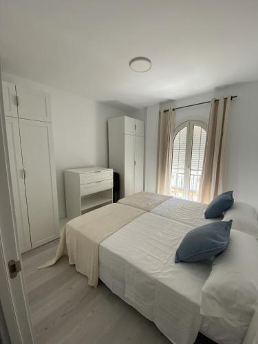 トレモリノスにあるApartamento Carihuelaのベッドルーム(青い枕の大きな白いベッド付)