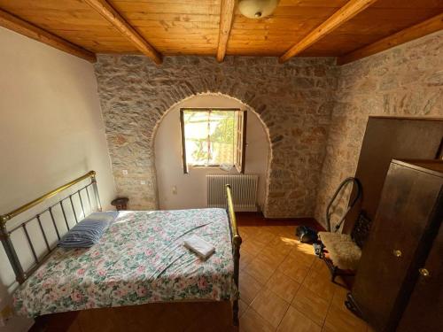 een slaapkamer met een bed in een kamer met een stenen muur bij Find your peace in a traditional country house!! in Lagia