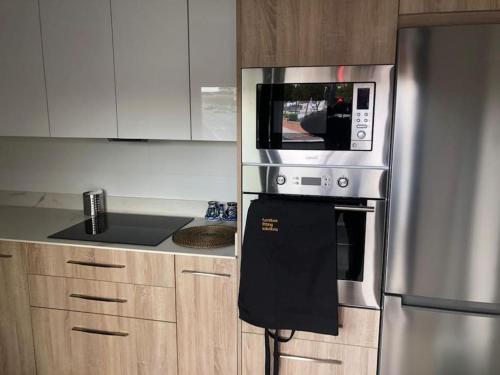 a kitchen with a stainless steel refrigerator and a microwave at Apartamento en Granada de nueva construcción con A/C y WIFI in Armilla