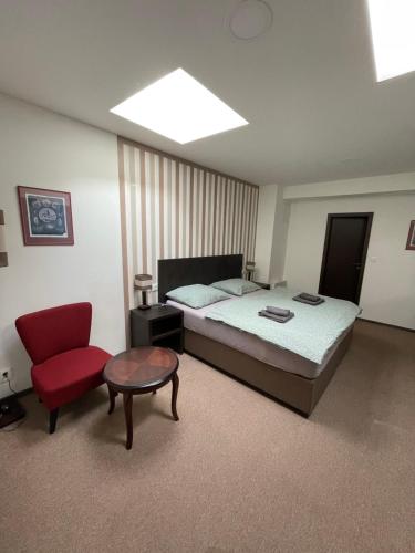 a bedroom with a bed and a red chair at Apartmán Ateliér in Kadaň