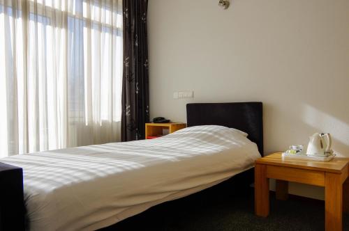a bedroom with a bed and a table and a window at Hotel and Restaurant van Saaze in Kraggenburg